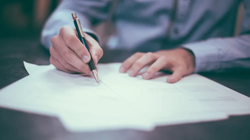 Music publishing paperwork and laptop showing sync licensing workflow on desk